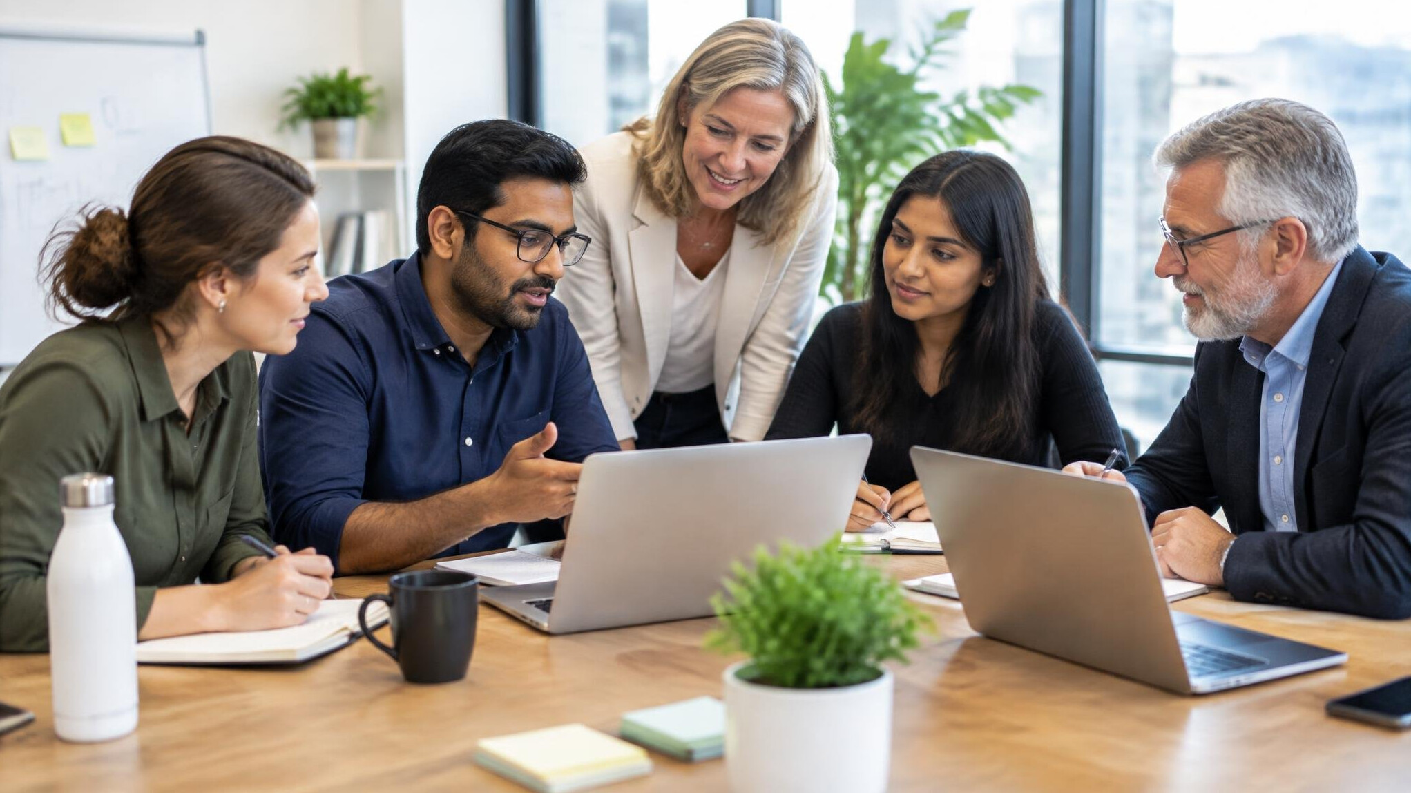 Team of colleagues collaborating around a table with laptops
